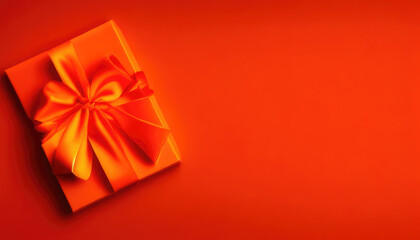 Flatlay of Valentines Day orange giftbox with red ribbon on orange background with copyspace