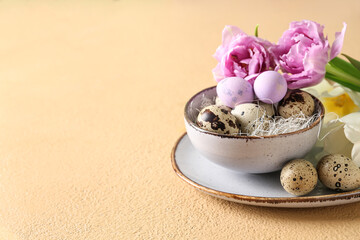 Bowl with Easter quail eggs and tulip flowers on beige table