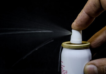 Close up view of a man spraying, A spray can  in a hand on a black background