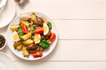 Plate of tasty potato salad with eggs and tomatoes on light background