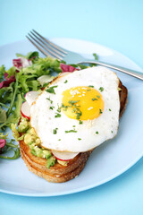 Delicious sandwich with fried egg and salad on blue background