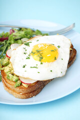 Delicious sandwich with fried egg and salad on blue background