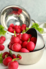 Bowls with fresh radish on light background