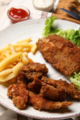Plate of tasty fried codfish with french fries on table, closeup