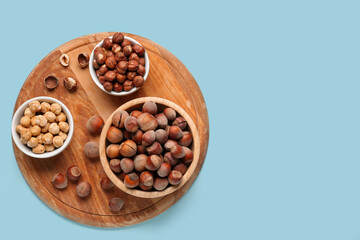 Board and bowls with hazelnuts on blue background