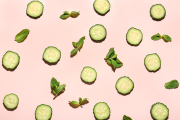 Slices of cucumber with mint on pink background