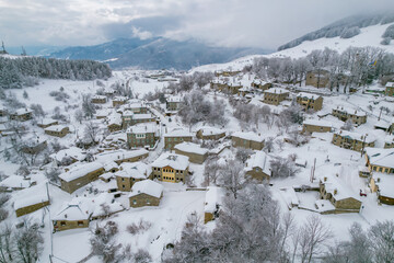 Aerial view of traditional architecture  with  stone buildings covered  with snow  during  winter season in the picturesque village of Nymfaio  Florinas, Greece