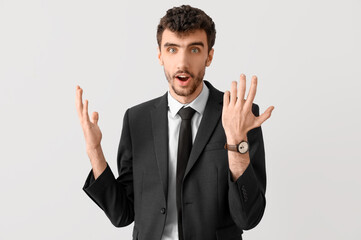 Surprised young businessman in suit on light background