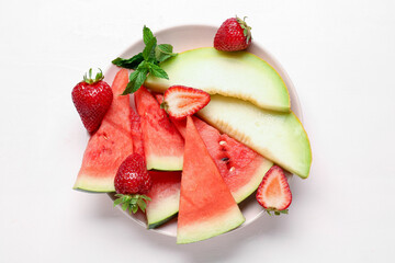 Plate with pieces of fresh watermelon and different berries on light background