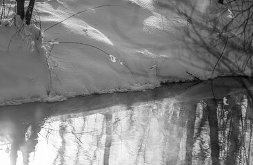 Snow ice on the river bank close-up, water flowing, winter.