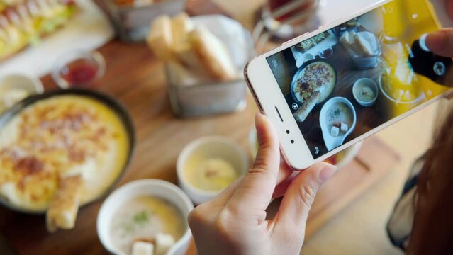 Take a photo of a smartphone for lunch or dinner. Woman taking picture with phone. Posting or sharing popular food for social media.