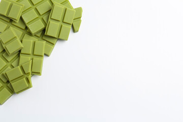 Pieces of tasty matcha chocolate bars on white background, top view. Space for text