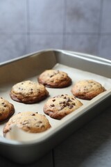 Baking pan with chocolate chip cookies on table, closeup