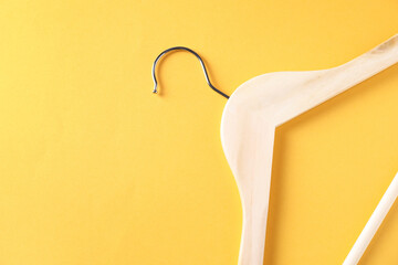 One wooden hanger on yellow background, top view. Space for text