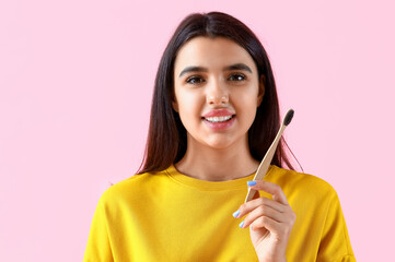 Smiling young woman with toothbrush on pink background, closeup