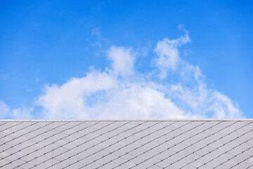 Roof tiles against clouds in the blue sky. - 708906965