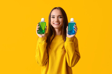 Smiling young woman with mouth rinse on yellow background