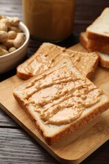 Delicious toasts with peanut butter on dark wooden table, closeup