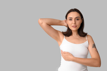 Young woman checking her breast on light background. Cancer awareness concept