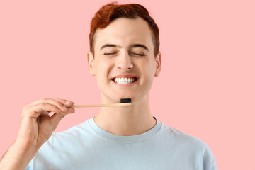 Young man with toothbrush on pink background, closeup