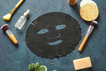 Facial sheet mask with different cosmetic products on dark background