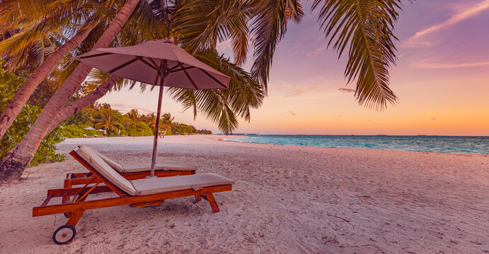 Beautiful honeymoon tropical sunset. Couple sun chairs umbrella under palm tree leaves. Romantic landscape sand, sea view horizon, colorful sunrise sky, calm love relaxation. Inspire beach resort