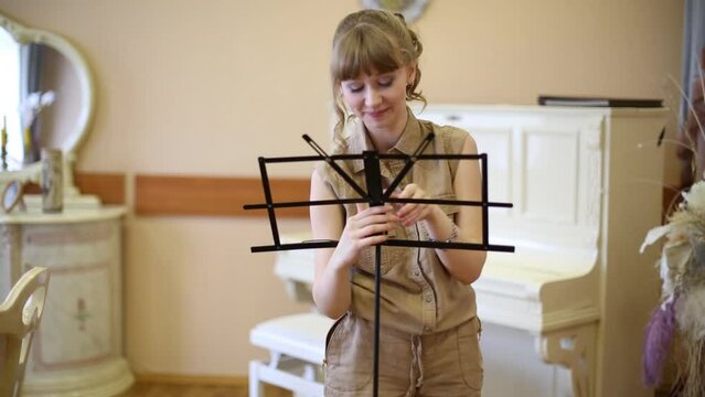 Beautiful girl installs music stand in room with classic interior