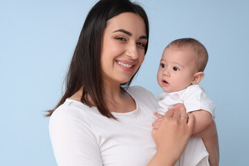 Happy mother with her little baby on blue background, closeup