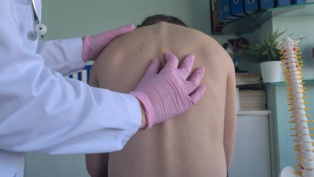 Chiropractor examining child with back pain in clinic. Postural disorders in children stoop and scoliosis