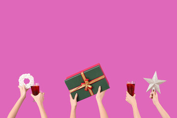 Female hands with glasses of warm mulled wine and Christmas decor on pink background
