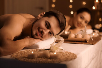 Young man with his wife relaxing in dark spa salon, closeup