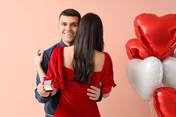Young engaged couple with wedding ring hugging on beige background. Valentine's Day celebration