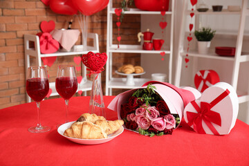 Festive table serving with wine glasses, croissants and bouquet of roses. Valentine's Day celebration