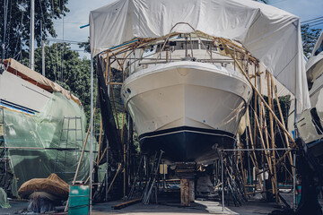 Motor yacht moored for repairs and service in dry dock - obrazy, fototapety, plakaty