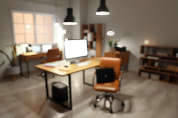 Blurred view of modern office with desks and glowing lamps