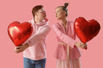 Young couple with heart-shaped balloons on pink background. Valentine's Day celebration