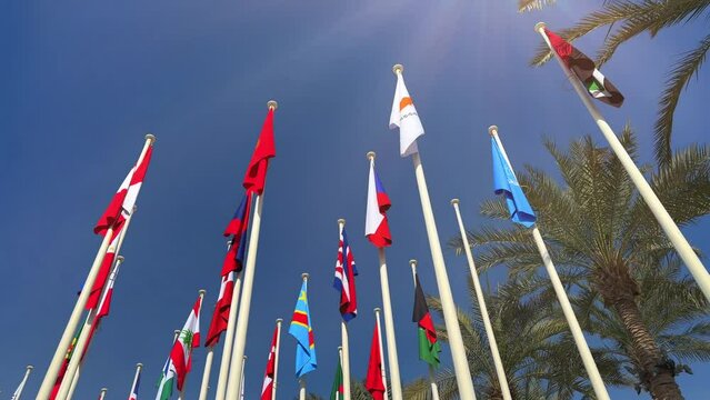 flags of all countries on a flagpole during the day against a background of blue sky and sunny people