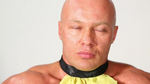 Closeup bald man in yellow dicky poses, grins and then winks.