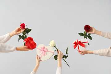 Female hands holding heart-shaped gift boxes and roses on white background. Valentine's Day...