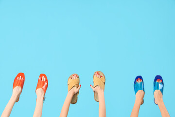 Female hands holding different sandals on blue background