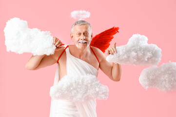 Mature man dressed as Cupid in clouds on pink background. Valentine's Day celebration