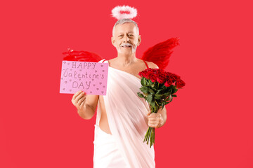 Mature man dressed as Cupid with card and roses on red background. Valentine's Day celebration