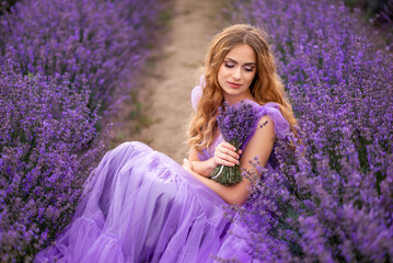 Portrait of a beautiful young woman with a bouquet of lavender in a field with purple flowers
