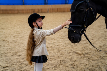 Cute little girl with horse on ranch. Jockey training countryside.