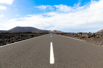 Panoramic view of empty asphalt road LZ-67 in volcanic landscape of Timanfaya National Park,...