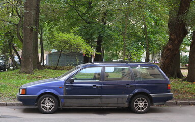 An old dark blue car is parked near the lawn, Tallinskaya Street, Saint Petersburg, Russia, September 26, 2023