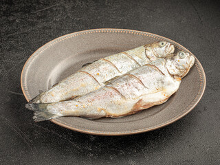 Two raw fish on a plate on grey background