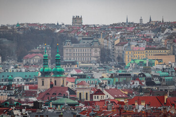 Naklejka na ściany i meble A cityscape view of the old historic medieval city of Prague with many rooftops. There is a church and a tower. It was freezing cold in winter