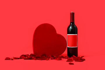 Bottle of wine with gift and rose petals on red background. Valentine's Day celebration