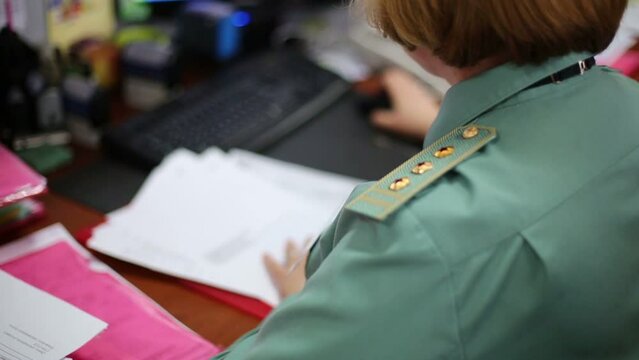 Female customs officer in uniform works at workplace